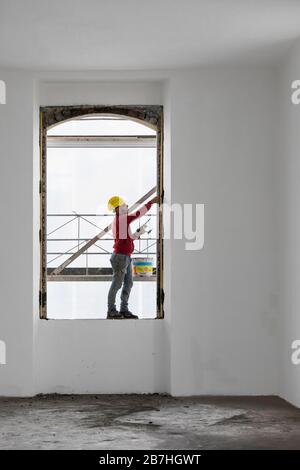 Worker balancing on a window while working. Building site Stock Photo