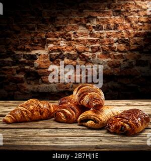 Fresh croissants on desk and free space for your decoration.Dark mood photo of wall with shadows.Copy space for your composition. Stock Photo