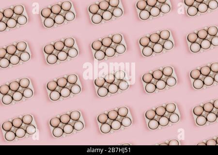 Pattern made with Organic eggs in carton tray on pastel pink backgroud. Zero Waste concept. Flat lay style. Stock Photo
