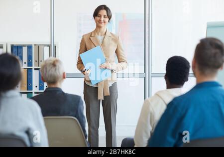 Portrait of successful young businesswoman giving speech to audience during seminar, copy space Stock Photo