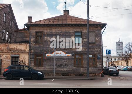Cars parked on the street in front of an old two-story wooden house in Riga, Latvia Stock Photo