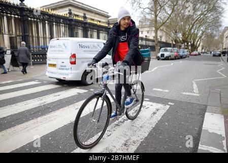 London, England, UK. Man on a bicycle riding over a pedestrian crossing in front of the British Museum Stock Photo