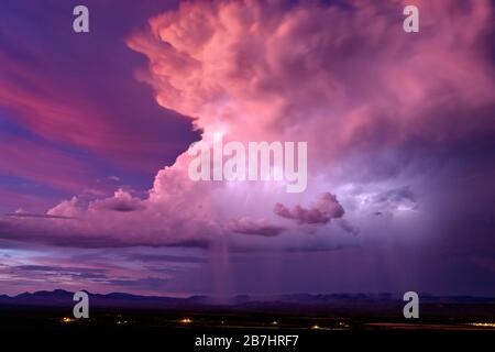 Arizona sunset with a dramatic thunderstorm cumulonimbus cloud illuminated by lightning at sunset, over the mountains near San Carlos Stock Photo