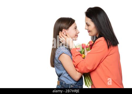 Happy Mother's Day, Women's day or Birthday background. Adorable girl giving mom bouquet of pink tulips. Studio portrait of a loving mother embracing Stock Photo