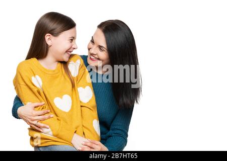 Waist up studio portrait of a mother and young daughter face to face laughing. Happy family laughing background isolated over white. Stock Photo