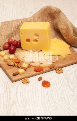 Different varieties of cheese on the board, grapes, dried apricots and nuts Stock Photo