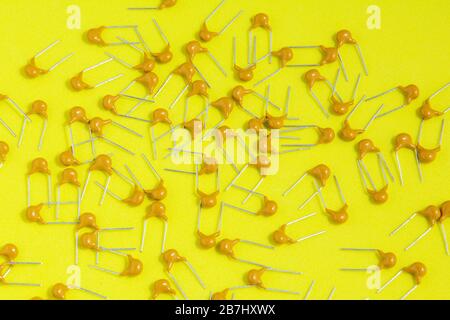 Electronic radio components, lots of ceramic tantalum capacitor on yellow background. Selective focus. Stock Photo