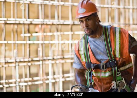 Dirty mid-adult construction worker wearing a helmet and hi-visibility vest. Stock Photo