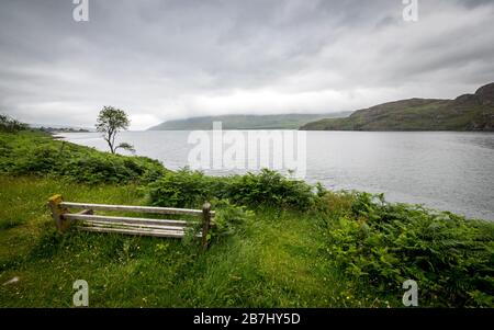 Loch Ewe viewpoint, Highlands, Scotland. A bench looking over the calm waters of Loch Ewe in the Scottish Highlands on a grey and overcast day. Stock Photo