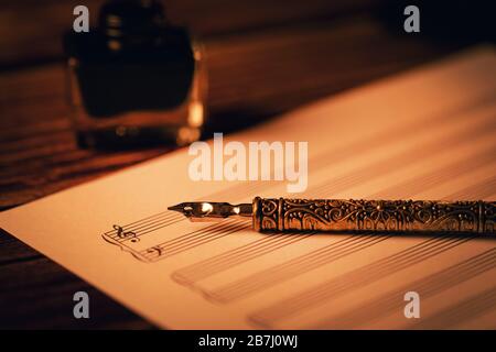 vintage quill pen on blank music notes sheet Stock Photo
