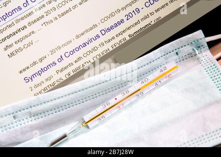Internet search by "Symptoms of  Coronavirus" with the medical syringe,medical face mask and thermometer with high temperature .Conceptual image Stock Photo