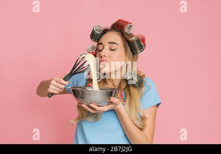 Housewife enjoys the smell food holding whisk and bowl in hands Stock Photo