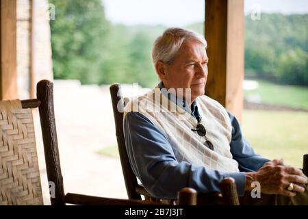 Older man sitting outdoors looking contemplative Stock Photo