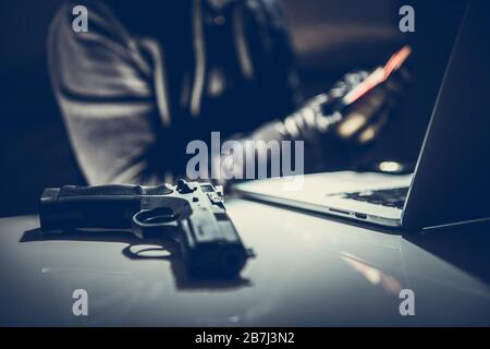 Online Hacking Gang . Handgun and Laptop on Desk. Cybercrime Concept Photo. Stock Photo
