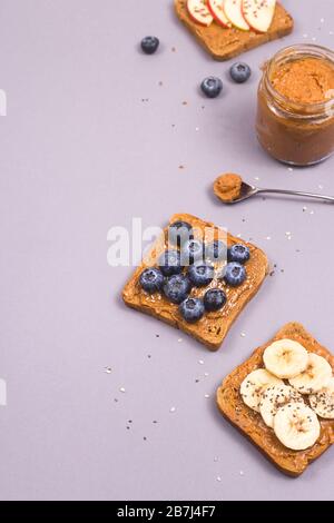Sandwiches with peanut butter and fruits and seeds on a gray background. Healthy vegetarian breakfast. Copyspace. Stock Photo