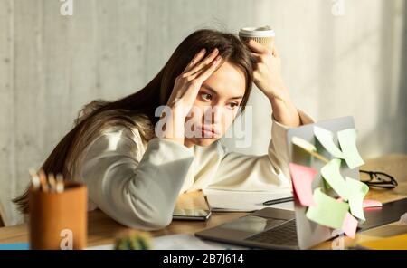 Freelance girl blowing lips and looks at laptop Stock Photo