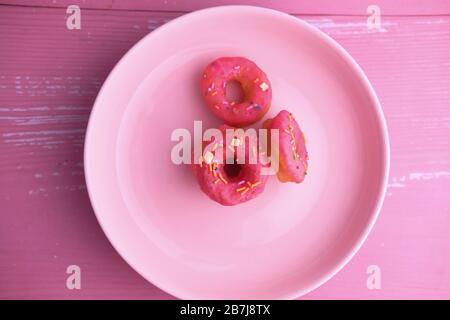 mix of multicolored sweet donuts on plate on color background Stock Photo