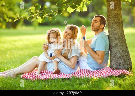 Happy family is hugging while sitting in the park. Stock Photo