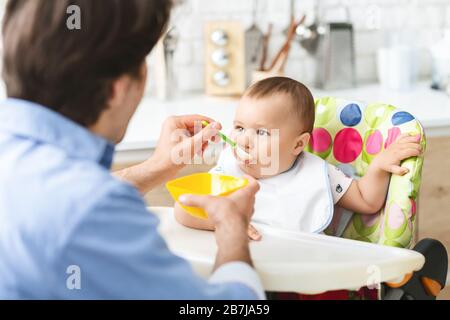 Toddler eating healthy kid food at kitchen interior Stock Photo