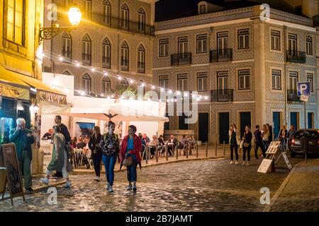 Tourists stroll cobblestone streets at night in the Alfama district, Lisbon, Portugal Stock Photo