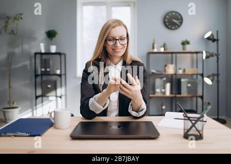 Cheerful lady using smartphone to solve business issues Stock Photo