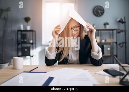 Tired lady stressing while working with paper documents Stock Photo