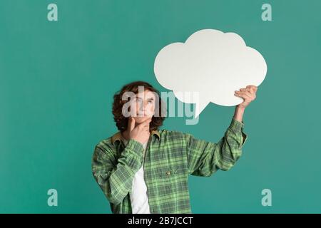 Dreamy millennial guy with speech bubble deep in thought on color background, space for text Stock Photo