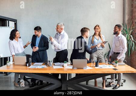 Diverse Colleagues Discussing Business Project Standing In Modern Office Stock Photo