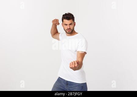 Young handsome man over isolated background Punching fist to fight, aggressive and angry attack, threat and violence Stock Photo