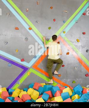 Teenage boy on climbing wall in trampoline center. Adventure and extreme for teenager concept Stock Photo