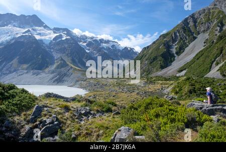 Man on Rock with Glaciers and snow-topped mountains and lake, Aoraki/Mount Cook National Park, South Island, New Zealand Stock Photo