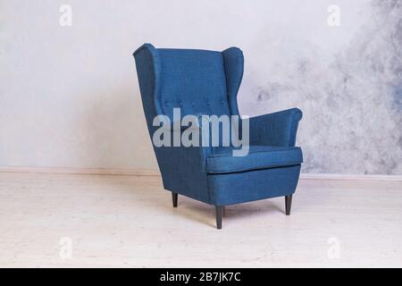 Classic blue chair. loft interior.Comfortable armchair against concrete wall background.Scandinavian style.Minimal Modern Furniture Recliner Object in Stock Photo