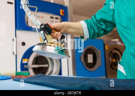 Female hand ironing blue jeans in a dry cleaning laundry service Stock Photo