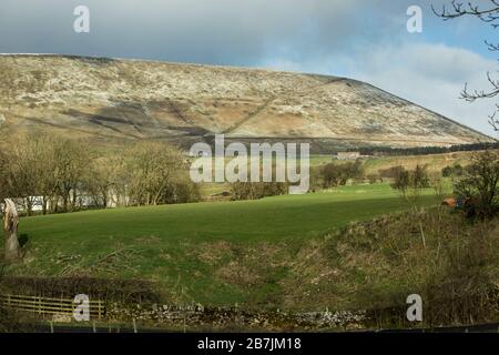 Snow covered Pendle Hill in winter with dark clouds and sunshine, Lancashire, England, UK Stock Photo