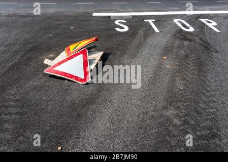 Warning sign exclamation mark in yellow triangle  and pay attention to the right of way sign on asphalt road with white stop sign Stock Photo