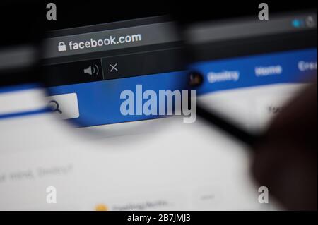 New-York , USA - March 13, 2020: Facebook homepage address view throw magnifier  close up Stock Photo