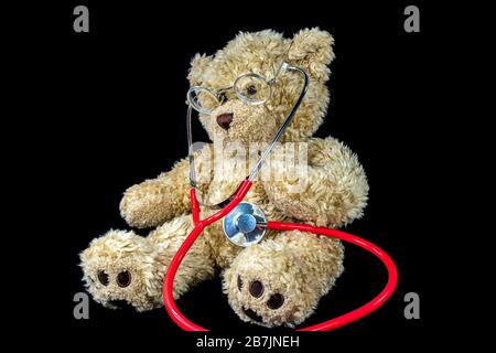 Brown fuzzy teddy bear with medical stethoscope on black Stock Photo