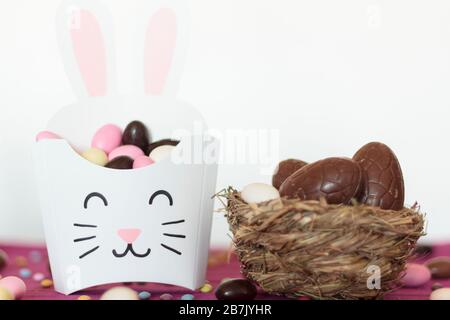 Bird nest with easter chocolate eggs and treat box with other easter candies Stock Photo