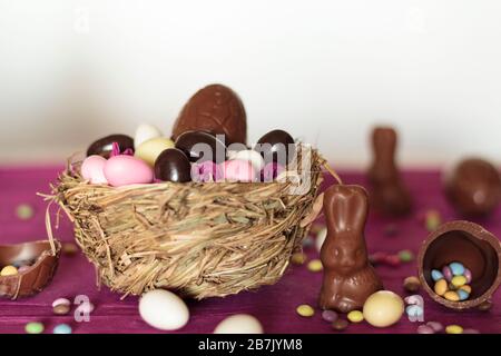Nest with chocolate eggs, chocolate bunny and sweets on easter table Stock Photo