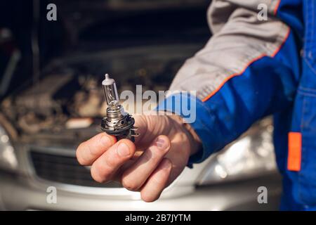 Car service men. Replacing a burnt out lamp in the car headlight. Stock Photo