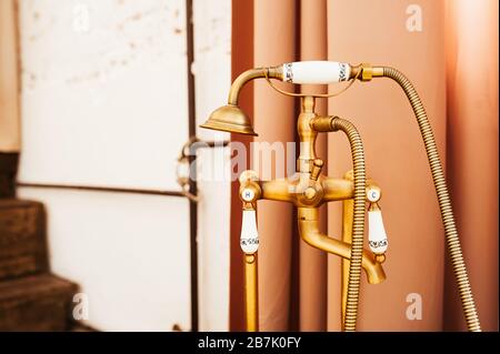 Old vintage gold faucet for hot and cold bath water and shower handle. Stock Photo