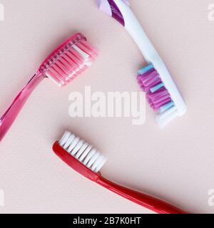 Top view of colored toothbrush with soft, medium, stiff bristles for daily use on light pink background. Stock Photo