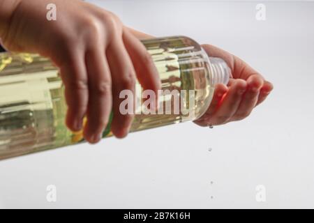 Little girl disinfecting hands with cologne. Turkish Lemon cologne with 80 degree alcohol for disinfection and killing the viruses on your hands. Stock Photo
