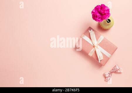 Gift box with carnation flower on pink background. Anniversary concept, flat lay, top view, copy space Stock Photo