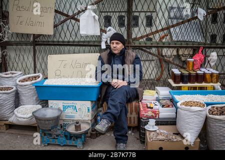 GNJILANE, GJILAN - JANUARY 2, 2016: Young man selling white navy beans (Pasul Tetoves) and nuts on the Gjilan bazaar, one of the biggest markets of Ea Stock Photo