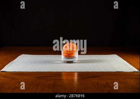 Isolated glass with sliced oranges inside on green mat ,black background Stock Photo