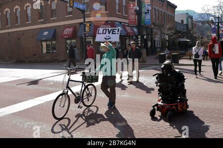 Man walking bicycle in a crosswalk carries 'Love' sign while Coronavirus voluntary social distancing precautions have been called for in United States Stock Photo