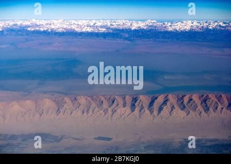 --FILE--An aerial view of the Taklamakan Desert, China's largest and world's 10th largest desert, with mountains whose tops are covered by snow, in Ka Stock Photo
