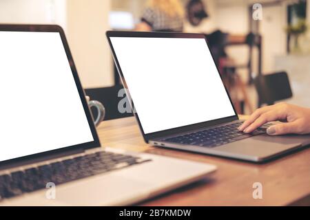 Mockup image of two laptop with blank white desktop screen on wooden table in office Stock Photo