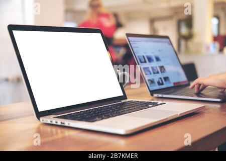 Mockup image of two laptop with blank white desktop screen on wooden table in office Stock Photo